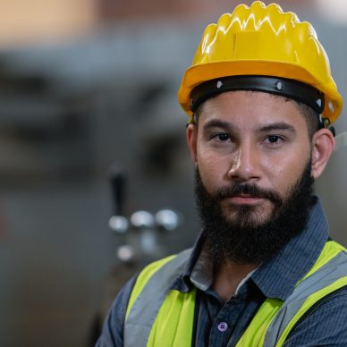 Portrait of man engineer wear yellow helmet and uniform standing Portrait of man engineer wear yellow helmet and uniform standing at industrial workshop. handsome workman with beard on face in factory. Copy space.